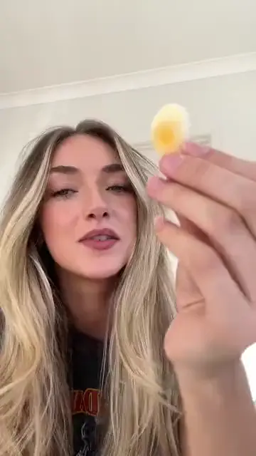 A woman holding a lolly up to the camera before tasting it